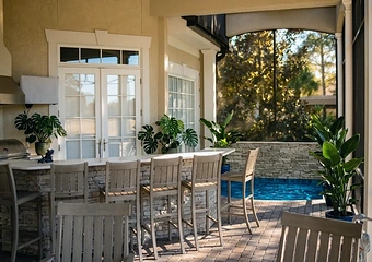 An outdoor kitchen and bar on a covered poolside terrace